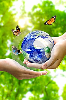 Woman hands holding world or globe give to another hand with butterfly on earth day.Environment conservation and energy saving