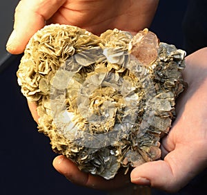 Woman hands holding yellow mineral siderite crystal cluster