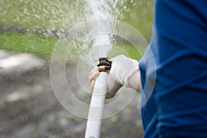 A woman hands with hosepipe watering her huge garden during lovely spring, summer time, hard work, senior gardening