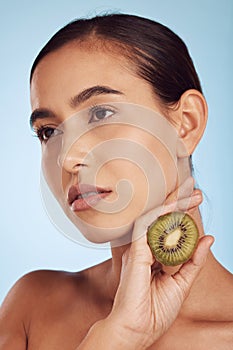 Woman, hands and kiwi in skincare for diet or natural nutrition against a blue studio background. Female person or model