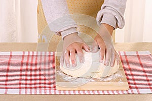 Woman hands knead dough on table in home kitchen