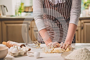 Woman hands kneading dough on kitchen table