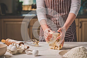 Woman hands kneading dough on kitchen table