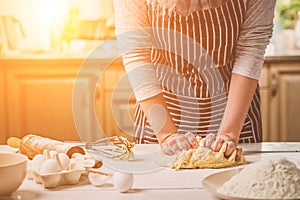 Woman hands kneading dough on kitchen table