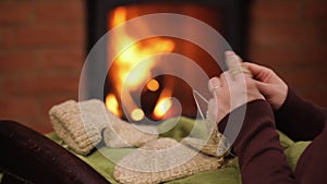 Woman hands knitting wool socks at the fireplace - closeup