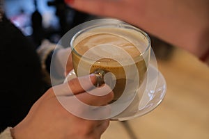 woman hands with latte on a wood table