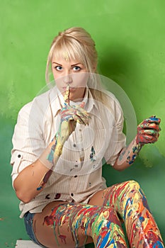 Woman with hands and legs covered with paint makes a hush and secret gesture