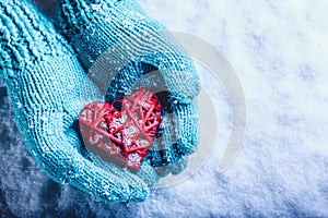 Una donna mani la luce lavorato maglia guanti Sono possesso bellissimo intrecciate antico cuore rosso la neve. San Valentino 