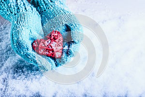Una donna mani la luce lavorato maglia guanti Sono possesso bellissimo intrecciate antico cuore rosso la neve. San Valentino 