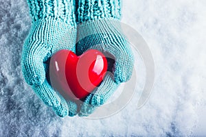 Una donna mani la luce lavorato maglia guanti Sono possesso bellissimo brillante cuore rosso la neve. San Valentino 