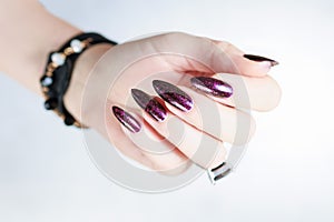 Woman hands with long nails and a bottle of dark red burgundy nail polish