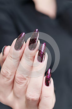 Woman hands with long nails and a bottle of dark red burgundy nail polish