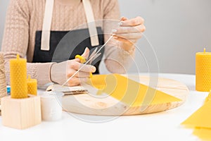 Woman hands make candles from yellow beeswax, top view