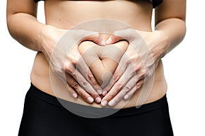 Woman hands make heart shape on stomach