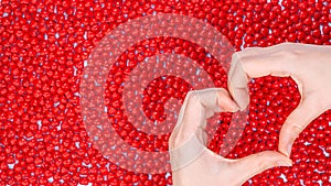 Woman hands making heart shape on red candy background. Heart from hands. Valentines Day concept. Symbol and shape of heart