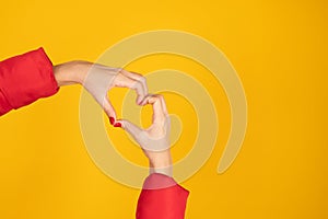 Woman hands making a heart shape on yellow background. Love sign, Valentines day concept.