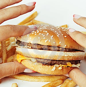 Woman hands with manicure holding hamburger and french fries isolated on white, food unhealthy