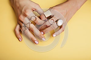 Woman hands with manicure and jewelry ring on yellow background, beauty style concept