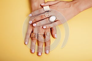 Woman hands with manicure and jewelry ring on yellow background, beauty style concept