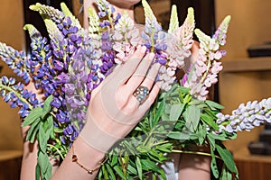 Woman hands with manicure and luxury jewelry rings. Close up of female hand on flowers showing fashion jewelry at camera