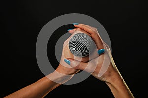 Woman hands with microphone isolated on black