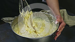 Woman hands mixing by whisk yeast dough with whisked yolks and whipped cream