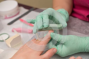 Woman hands in a nail salon receiving a manicure. Nail filing. Close up