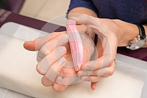Woman hands in a nail salon receiving a manicure. Nail filing. Close up