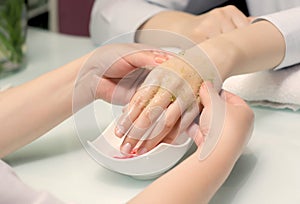 Woman hands in a nail salon receiving a manicure. SPA scrub and peel for hands.