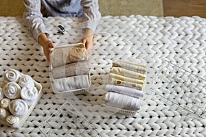 Woman hands neatly folded linens and towels use Marie Kondo method with sticky label tags