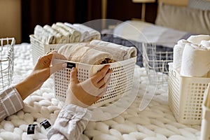 Woman hands neatly folded linens and towels use Marie Kondo method with sticky label tags