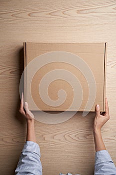 Woman hands open empty cardboard box, top view