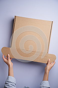 Woman hands open empty cardboard box, top view