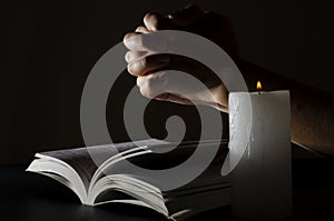 Woman hands, opened Bible and candle flame.Concept of praying to God