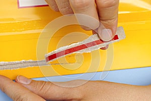 Woman hands opening mail package with easy open strip