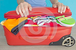 Woman hands packing stuff into suitcase at home. Suitcase with things for spending summer vacation things prepared for travel