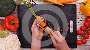 Woman hands peel fresh carrot - slow motion