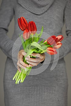 Woman hands with perfect nail art holding pink spring flowers tulips, sensual studio shot