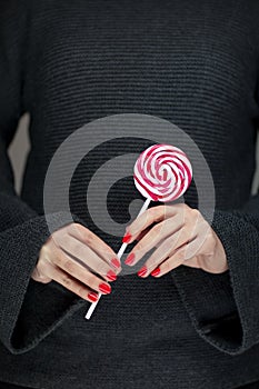 Woman hands with perfect nail polish holding some pink and white lollypops photo