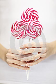 Woman hands with perfect nail polish holding some pink and white lollypops photo