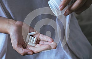 Woman hands with pills on spilling pills out of bottle,Female hand holding a medicine