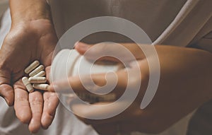 Woman hands with pills on spilling pills out of bottle,Female hand holding a medicine