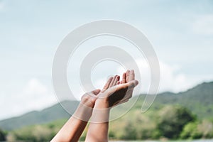 Woman hands place together like praying in front of nature green  background