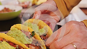 Woman hands placing hard shell tacos on serving plate
