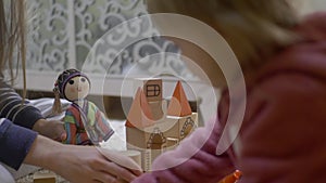 Woman hands playing with wooden blocks and a doll, showing kid how to build