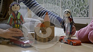 Woman hands playing at wooden blocks with dolls, showing kid how to act