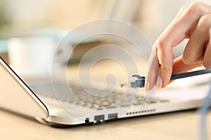 Woman hands plugging ethernet cable on laptop