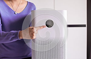 Woman hands pointing to screen of white modern air purifier in a living room for refresh air flow at home,Advanced air purifying a