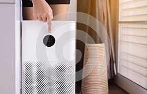 Woman hands pointing to screen of white modern air purifier in a living room for refresh air flow at home,Advanced air purifying a