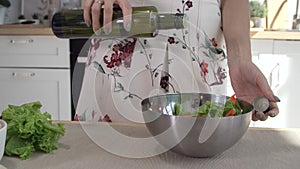 Woman hands pouring olive oil into glass bowl with fresh spring salad. Close up cooking woman hands. Healthy lifestyle